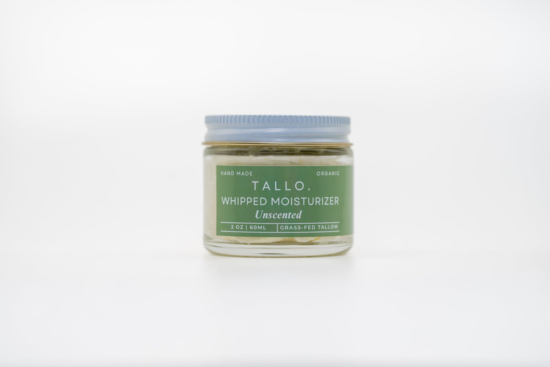A closed 2 oz glass jar of Tallo Unscented Whipped Moisturizer. The jar describes the size, ingredients, and handmade nature of the skincare.