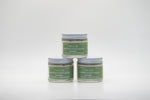 A set of three small glass jars of Tallo Whipped Moisturizer with green labels and white lids, stacked in a pyramid formation. The labels r The product is labeled as handmade, organic, and made with grass-fed tallow.d "Lavender"