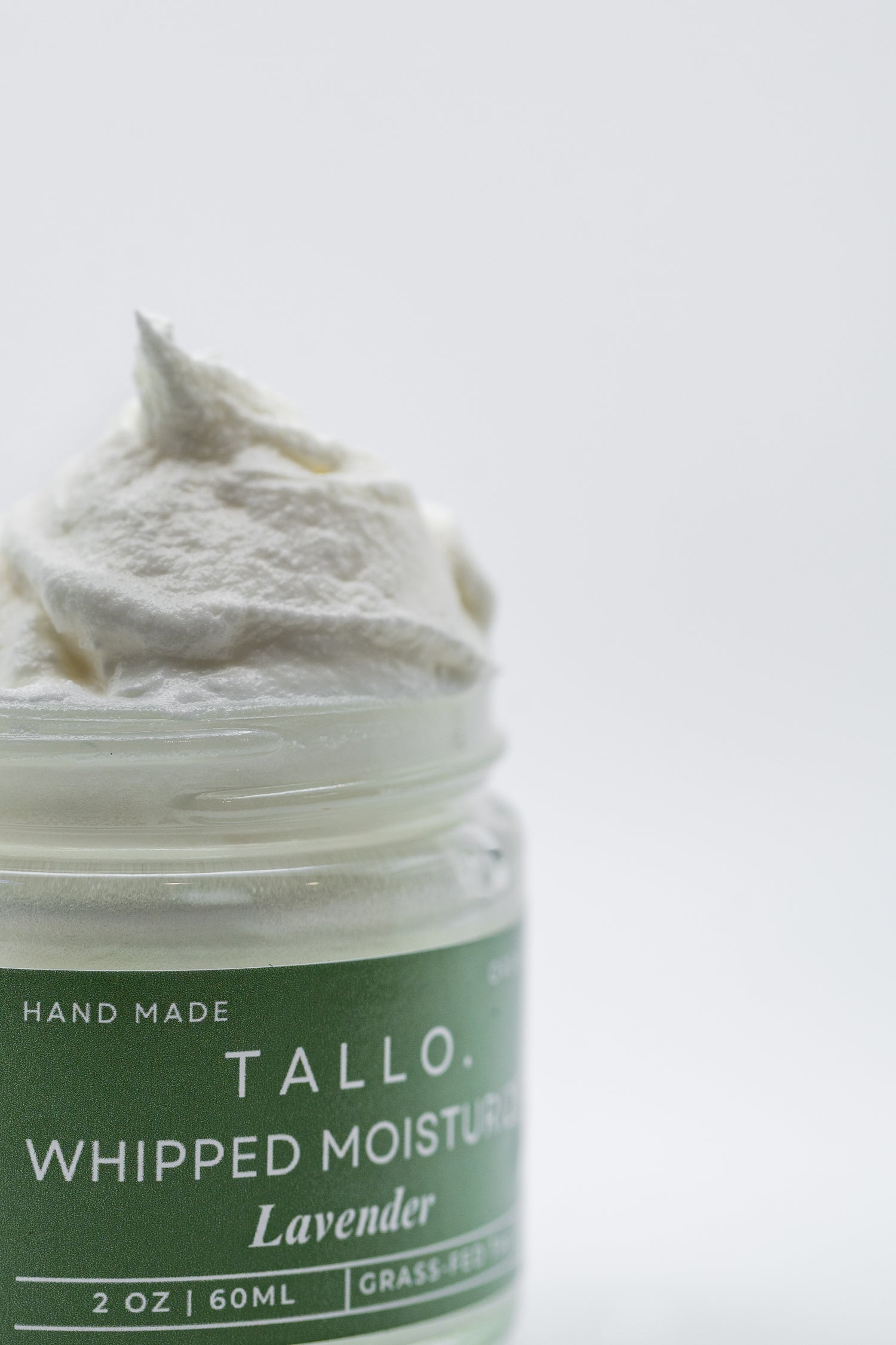 2 oz green glass jar of Tallo Whipped Lavender Moisturizer with the lid off. The hydrating and organic moisturizer is overflowing on the top of the jar helping display its smooth texture