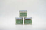 A set of three small glass jars of Tallo Whipped Moisturizer with green labels and white lids, stacked in a pyramid formation. The labels indicate different variations: Frankincense, Lavender, and Unscented. The product is labeled as handmade, organic, and made with grass-fed tallow.