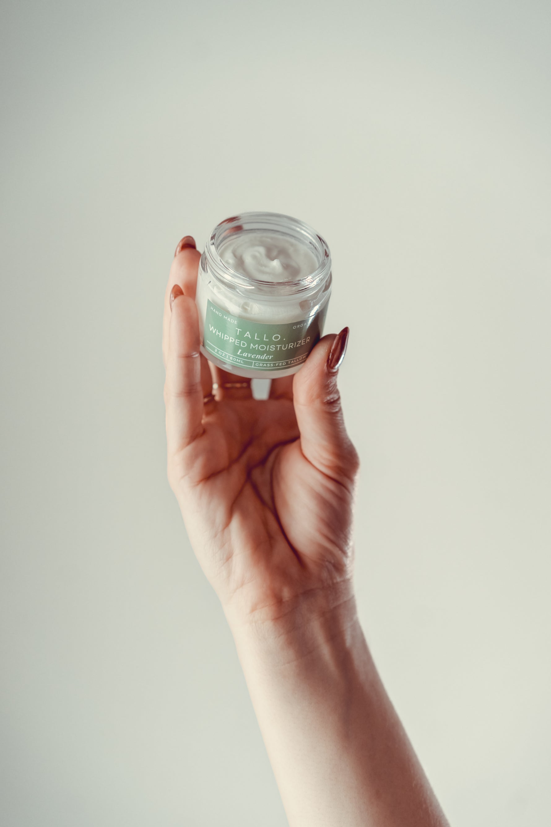 Hand holding a jar of TALLO Whipped Tallow Moisturizer in Lavender scent – natural, organic, grass-fed tallow skincare with a rich, whipped texture for face and body hydration.