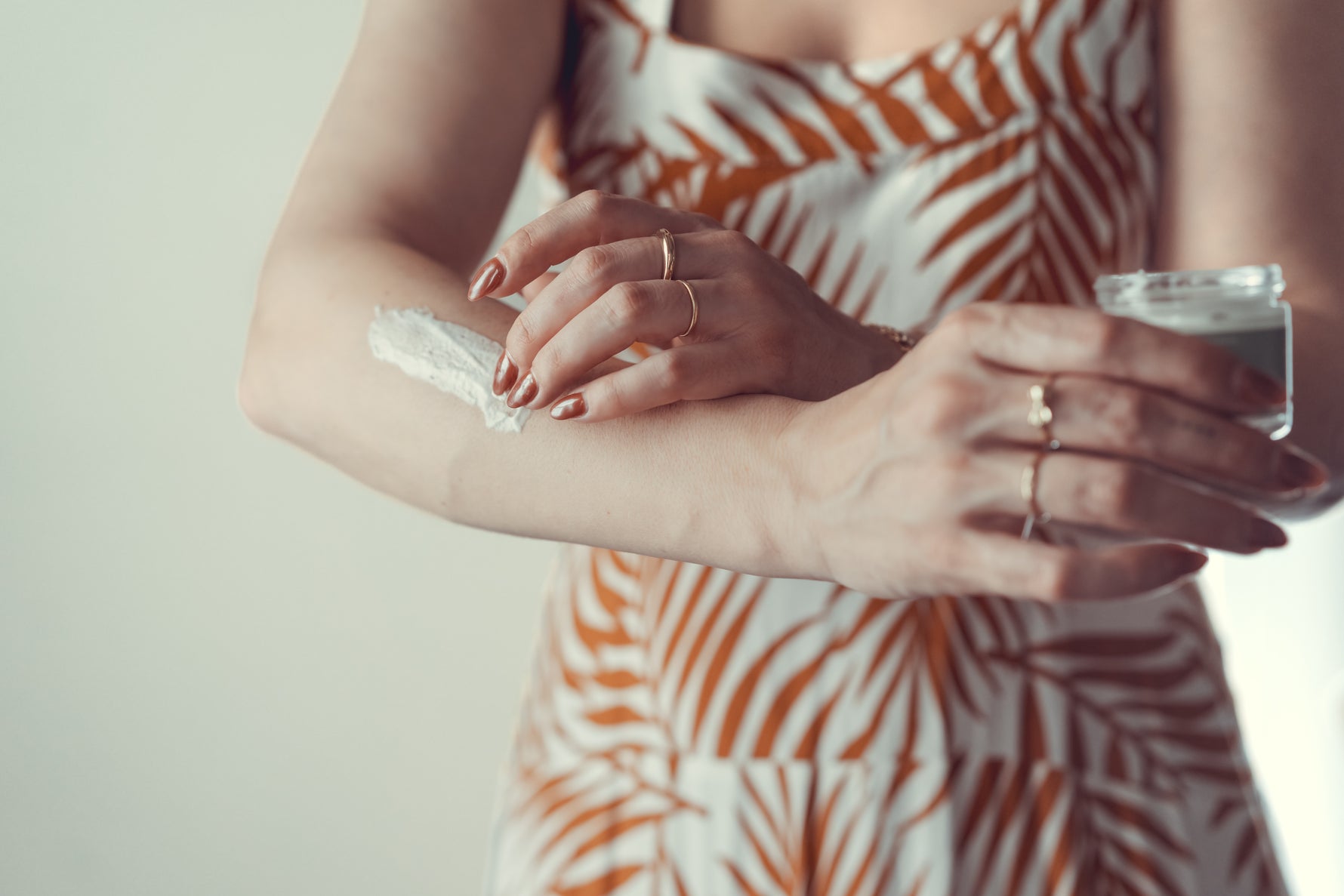 Tallo Skincare is being applied to a female's arm to show the texture of the skincare. She is holding a 2oz jar of Tallo Whipped moisturizer with the lid off.