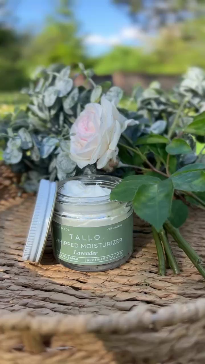 2 oz jar of Tallo Lavender Whipped Moisturizer with a green label and pink flowers draped alongside the jar. Light smelling, nourishing, and hydrating skincare.